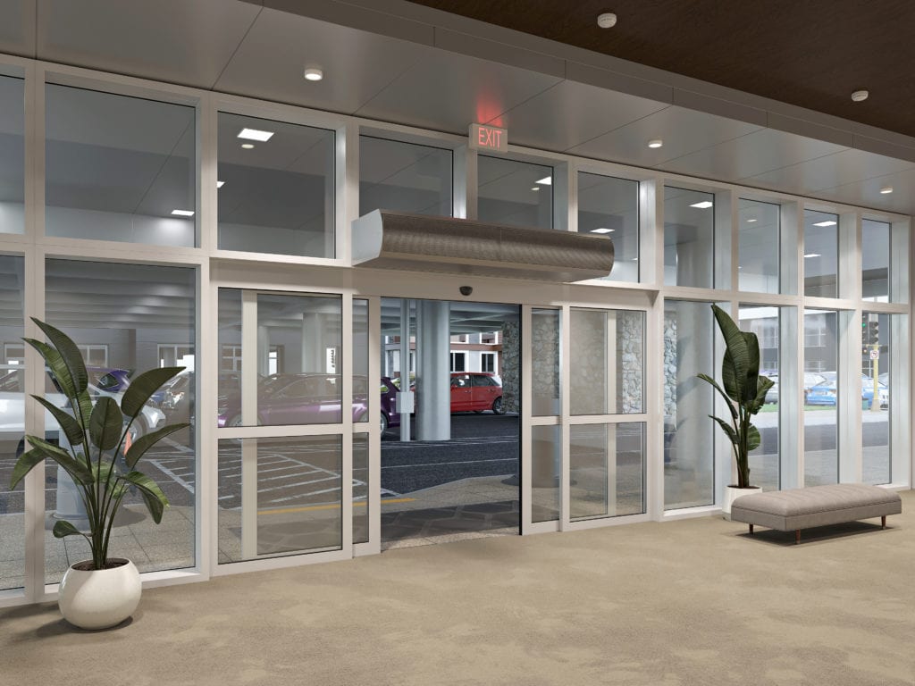 An entrance area featuring automatic glass doors, surrounded by large windows. Two potted plants are placed on either side of a bench. Parking spaces and vehicles are visible through the entrance.