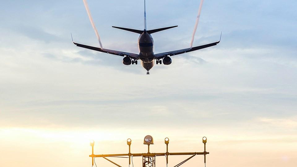 An airplane flying over an airport control tower